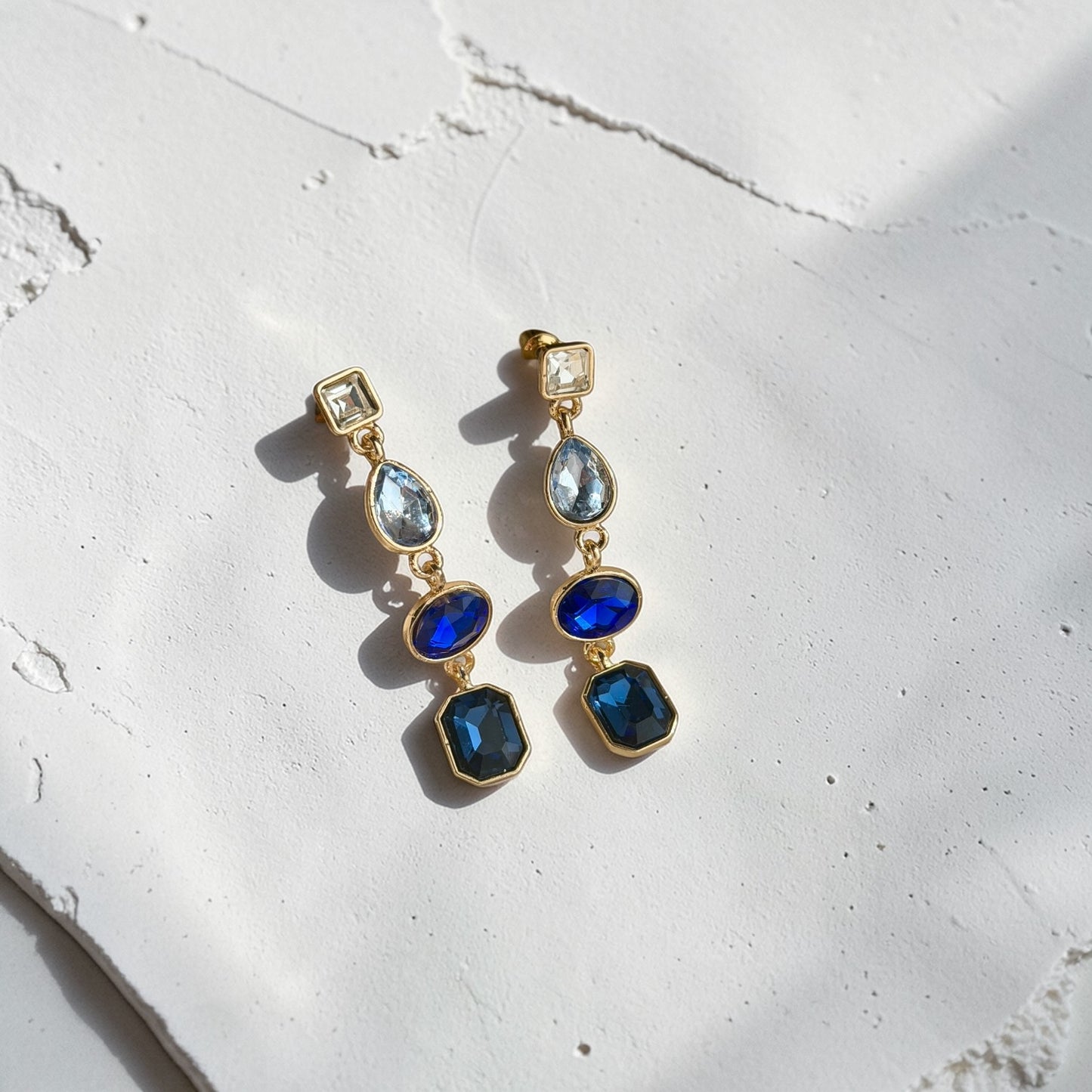 Sapphire Blue Four-Stone Drop Earrings Gold Tone — angle highlighting drop and movement