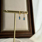 Baguette Blue Crystal Huggie Hoop Earrings 14K Gold on neutral background — front view