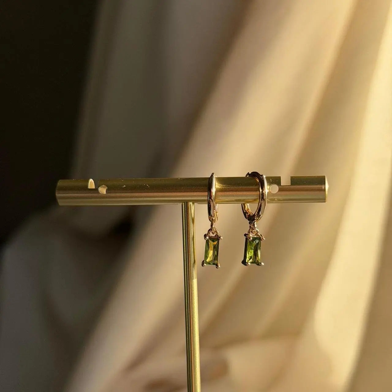 Olive Green Baguette Crystal Huggie Earrings 14K on neutral background — front view