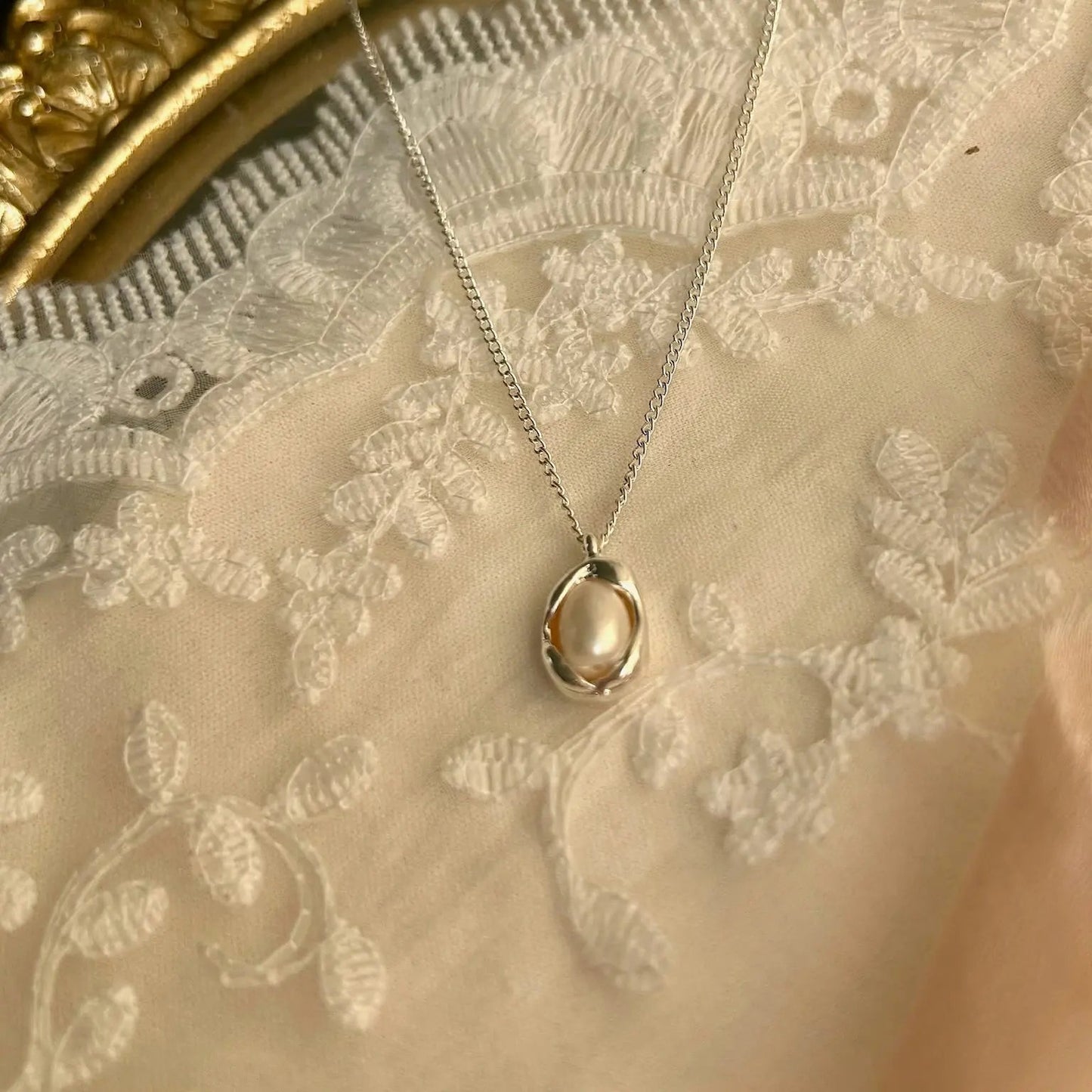 Freshwater Pearl Oval Pendant Necklace Silver Tone — styled flat lay with textures